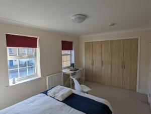 a bedroom with a bed and a desk and windows at 83 in Bournemouth