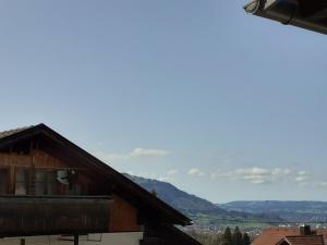 Vistas a una casa con montañas en el fondo en Berggasthof Sonne Allgäu en Sonthofen