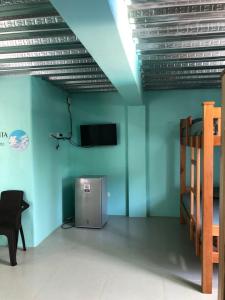 Habitación con paredes azules, TV y silla. en CABAÑAS CRAZY COCONUTS, en San Antero