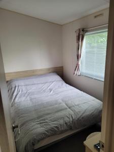a bed in a small room with a window at Highfield Grange Holiday Park in Little Clacton