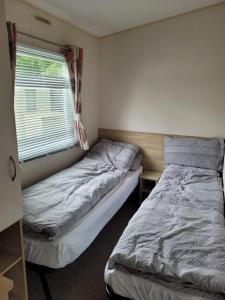 two beds in a small room with a window at Highfield Grange Holiday Park in Little Clacton