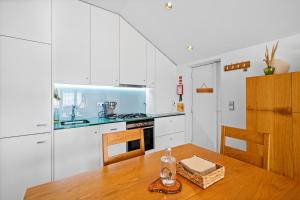 a kitchen with white cabinets and a wooden table at Seascape Apúlia in Apúlia