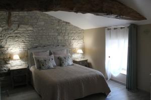 um quarto com uma cama e uma parede de pedra em La Douce Charentaise em Mérignac