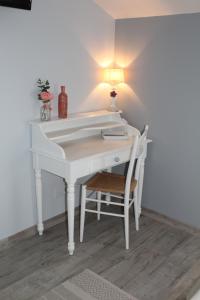 een wit bureau met een lamp en een stoel bij La Douce Charentaise in Mérignac