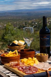 una mesa con una botella de vino y queso y una copa en AYRES SUITE en Villa Carlos Paz