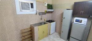een kleine keuken met een wastafel en een koelkast bij منزل صحم in Al Quşayr