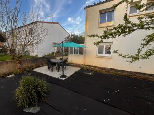 a patio with a table and a blue umbrella at Comme à la maison in La Roche-sur-Yon