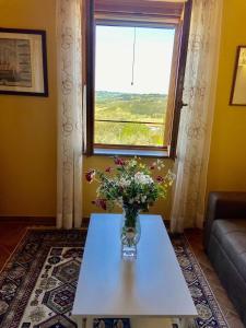 eine Vase mit Blumen auf einem Tisch vor einem Fenster in der Unterkunft Peccioli - The Tuscany Nest in Peccioli