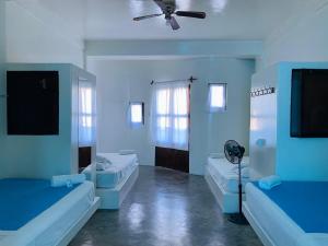 Habitación azul con 2 camas y ventilador. en Loki del Mar en Máncora