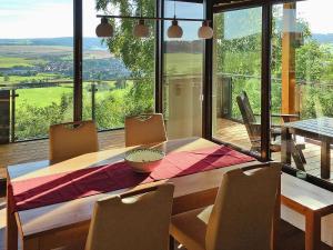 a dining room table with chairs and a large window at Attraktives Ferienhaus mit Balkon in Kaltennordheim