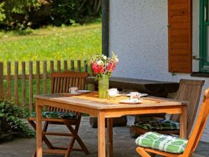 a wooden table with two chairs and a vase of flowers at Waldhaus Sonnenberg Apartment 2 in Drachselsried