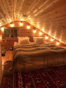 ein großes Bett in einem Holzzimmer mit Beleuchtung in der Unterkunft Villa Aiku in Leppäjärvi