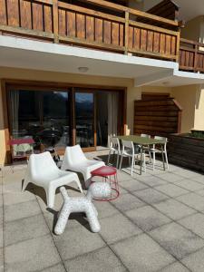 a patio with white chairs and tables and a deck at Appartement cosy Briançon in Briançon