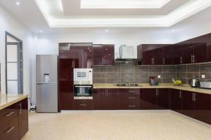 a large kitchen with wooden cabinets and stainless steel appliances at Residence Mandela Almadies Dakar, Senegal, Ngor Almadies in Ngor
