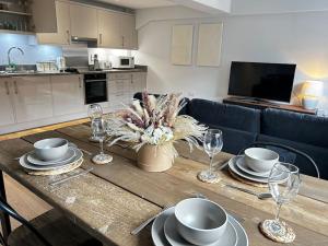 a wooden table with plates and wine glasses on it at Trendy City Centre Apartment with FREE Parking in Southampton