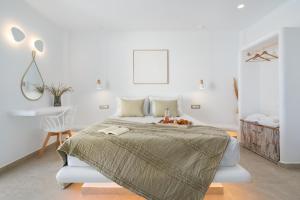 a white bedroom with a bed and a chair at Electra Suites & Spa in Perivolos