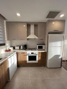 a kitchen with a white refrigerator and wooden cabinets at Villa West Park, Kyrenia in Kyrenia