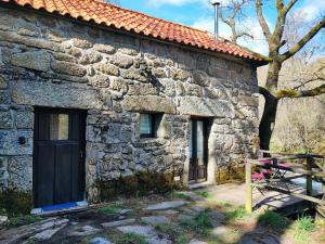 an old stone building with a door and a bench at Moinhos do Poço Verde - Nova Gestão in Castro Laboreiro