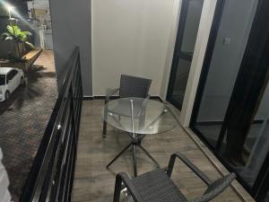 a glass table and two chairs on a balcony at Steady State Apartment 1 in Lusaka