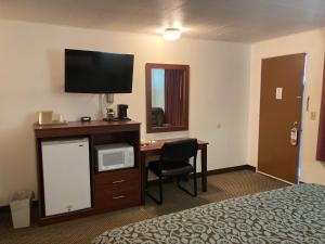 una camera d'albergo con letto e scrivania con TV di Hills Inn a Hot Springs