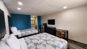 een slaapkamer met een bed, een bureau en een televisie bij Scottish Inn & Suites in Wharton