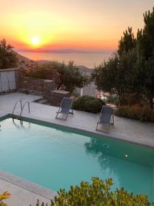 a pool with two chairs and a sunset in the background at AEGEAN WINGS MAISONETTE in Ioulida