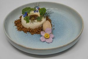 un plato con un postre con una flor en él en Le Paysan Horloger en Les Bois