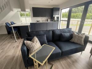 uma sala de estar com um sofá preto e uma cozinha em Inverness luxury highland NC500 hideaway em Inverness