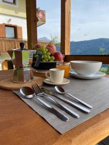 a table with utensils and a bowl of fruit at Appartamento da Romano - nel cuore delle Dolomiti in Danta