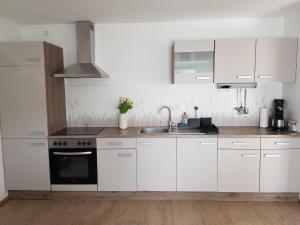 eine Küche mit weißen Schränken und einer Spüle in der Unterkunft Ferienwohnung Alte Landstube in Hürtgenwald