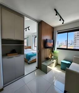 a bedroom with a bed and a room with a tv at H.E 704 · Comodidade no Caminho Das Árvores in Salvador