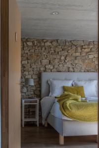 ein Schlafzimmer mit einem Bett mit einer Steinmauer in der Unterkunft Le Paysan Horloger in Les Bois