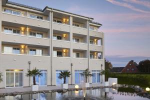 a large white building with palm trees in front of it at nordica Hotel Friesenhof in Büsum