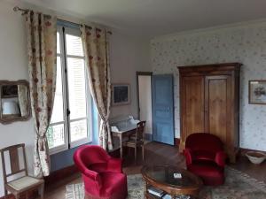 ein Wohnzimmer mit roten Stühlen und einem Tisch in der Unterkunft Le Chateau du grand Coudray in Villaines-la-Juhel