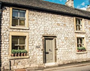 Granby Cottage, Peak District National Park في تيديسويل: مبنى من الطوب مع نافذتين وباب