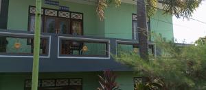 a green and blue building with windows and a palm tree at New KAMI Homestay in Banyuwangi