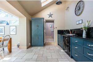 Granby Cottage, Peak District National Park في تيديسويل: مطبخ مع دواليب زرقاء وساعة على الحائط