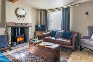 Granby Cottage, Peak District National Park في تيديسويل: غرفة معيشة مع أريكة ومدفأة