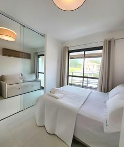 a white bedroom with a large bed and a window at Conforto no Caminho das árvores in Salvador