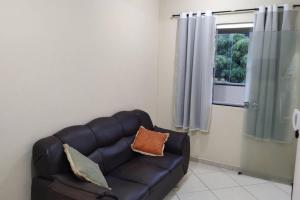sala de estar con sofá de cuero y ventana en Acomodação paraju-apartamento em caratinga en Caratinga