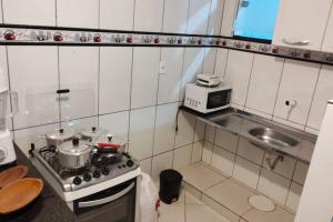 a small kitchen with a stove and a microwave at Acomodação paraju-apartamento em caratinga in Caratinga