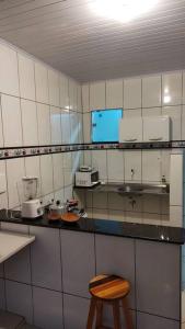 a kitchen with a counter and a wooden stool at Acomodação paraju-apartamento em caratinga in Caratinga