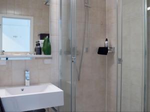 una doccia con porta in vetro accanto a un lavandino bianco di VISIONAPARTMENTS Chemin des Epinettes - contactless check-in a Losanna