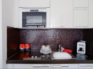 a kitchen counter with a sink and a microwave at VISIONAPARTMENTS Chemin des Epinettes - contactless check-in in Lausanne