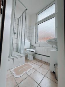 a bathroom with a toilet and a window and a rug at Dions Rooms in Norderney