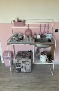um quarto rosa com uma prateleira com pratos e um lavatório em Giroloft em Cagliari