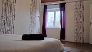 Schlafzimmer mit einem Bett und einem Fenster mit lila Vorhängen in der Unterkunft Maison de l'harmonie à Limoges in Limoges