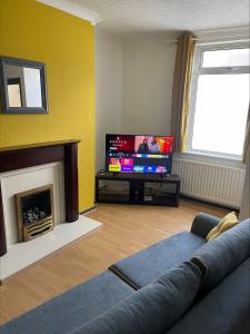 a living room with a couch and a tv at Quirky and Cosy Two Bed in Ferryhill Near Durham! in Ferryhill