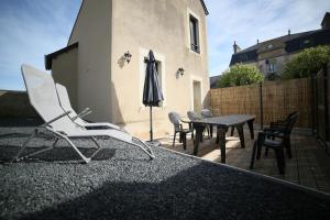 a patio with a table and chairs and an umbrella at Villa Joséphine 4-11 personnes in Asnelles