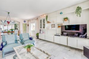 a living room with a tv and blue chairs at Hanami Alcazaba Beach Duplex Sea View in Estepona